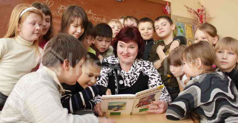 Учитель начальных классов читает книгу ученикам