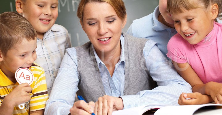 Учитель начальных классов проверяет работы учеников Профессия учитель